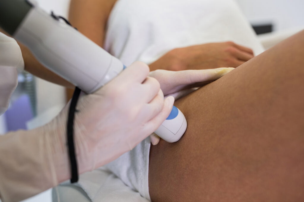 Woman receiving laser epilation treatment on her thigh at beauty salon